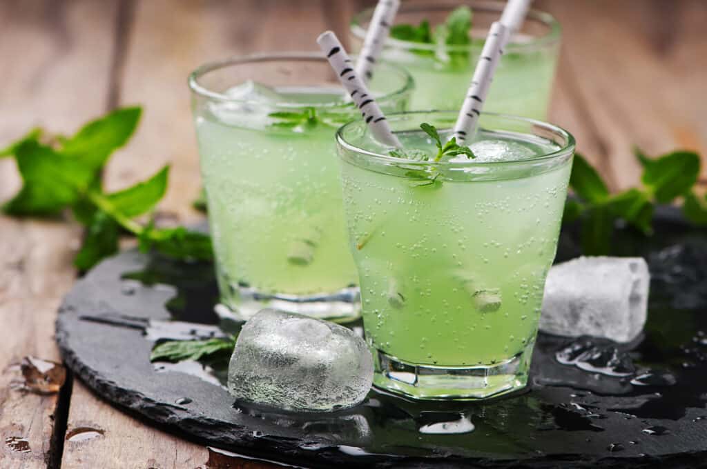 A icey glass holding green liquid and mint