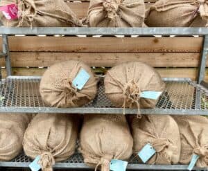 a wire rack with several burlap bags of potting soil 